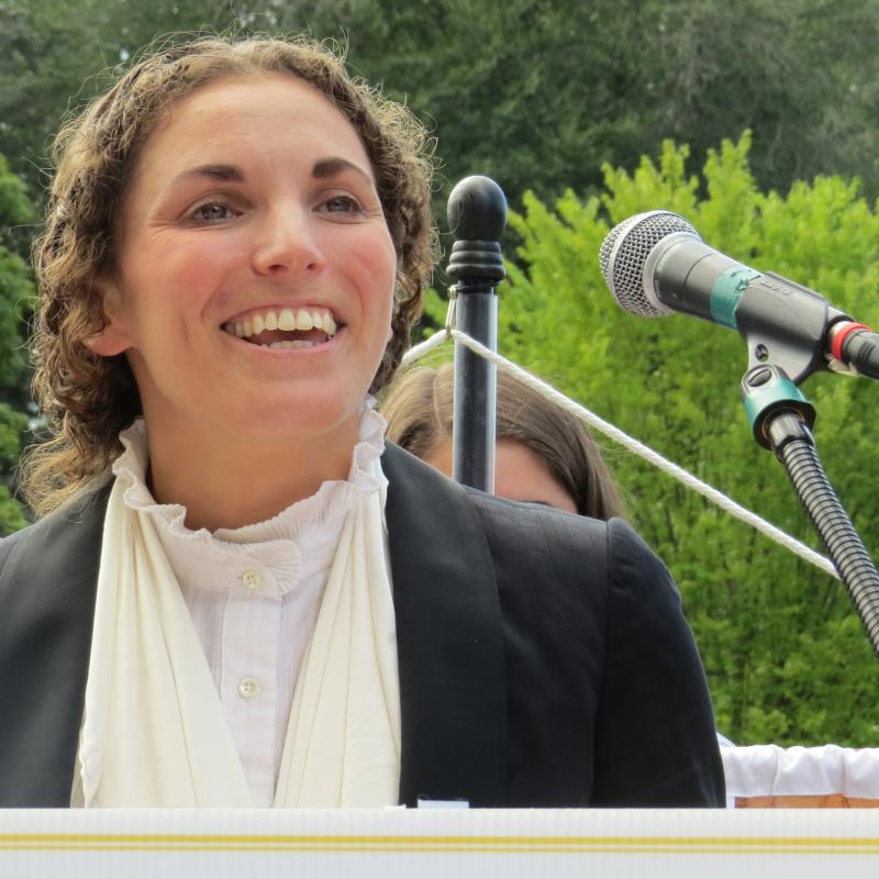 Woman stands at podium speaking.