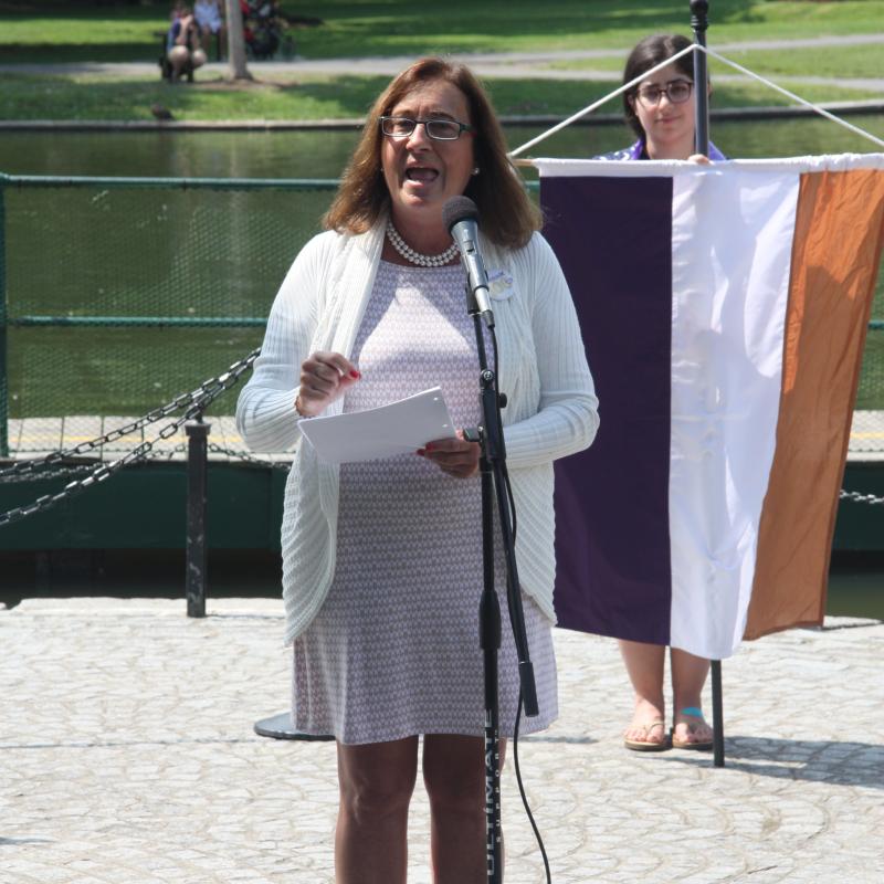 Woman speaking outside at microphone.