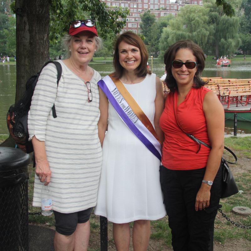 Three women stand outside smiling.