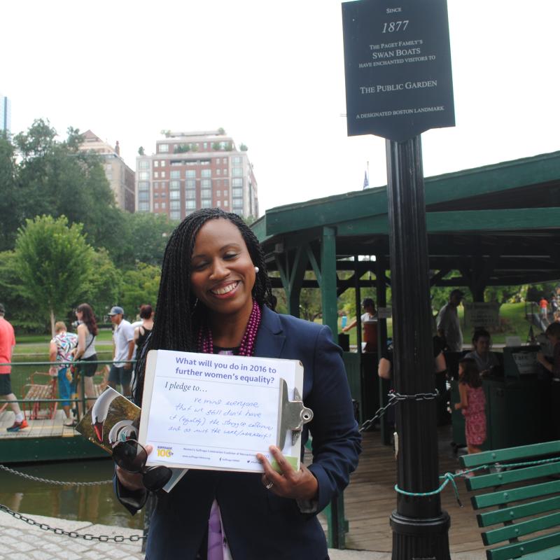 Woman stands outside holding certificate.