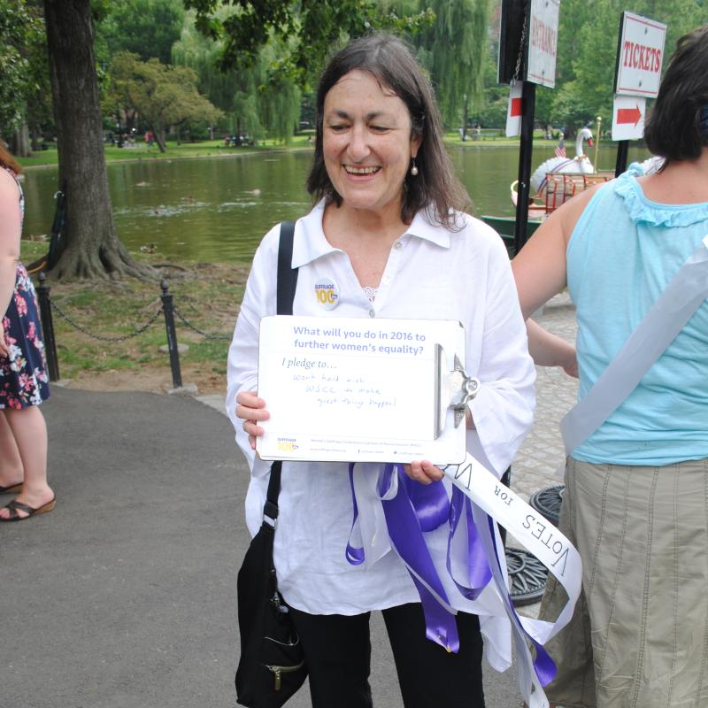 Woman stands outside holding certificate.