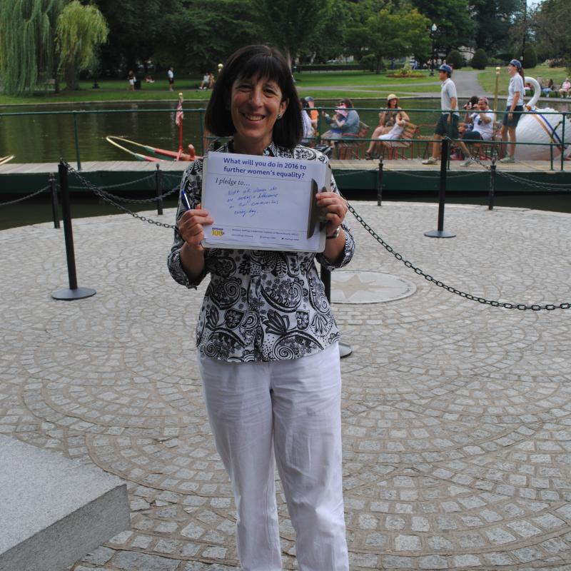 Woman stands outside holding certificate.