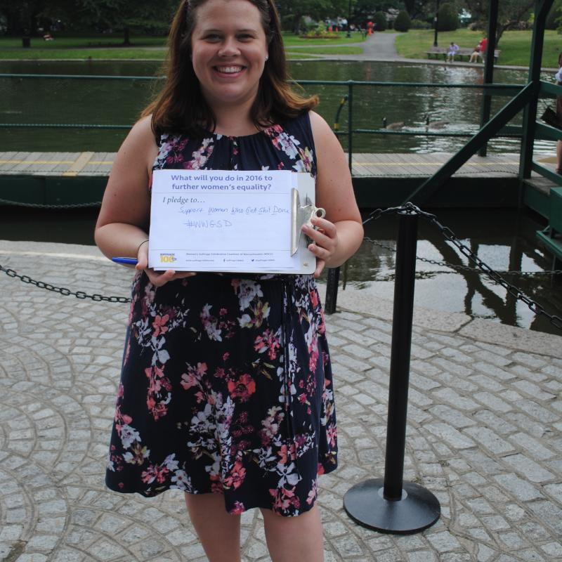 Woman stands outside holding certificate.