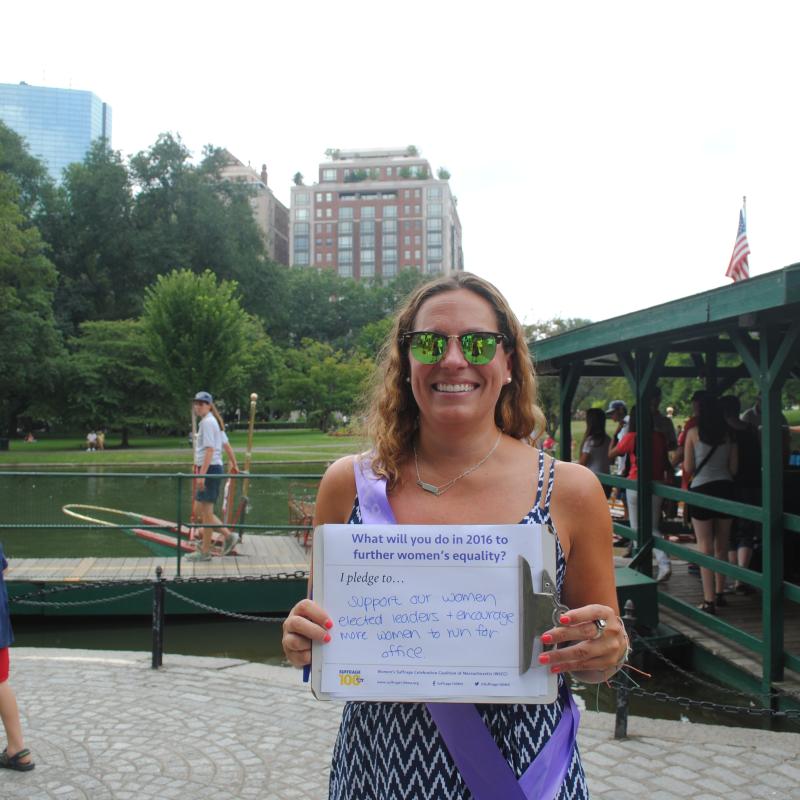 Woman stands outside holding certificate.