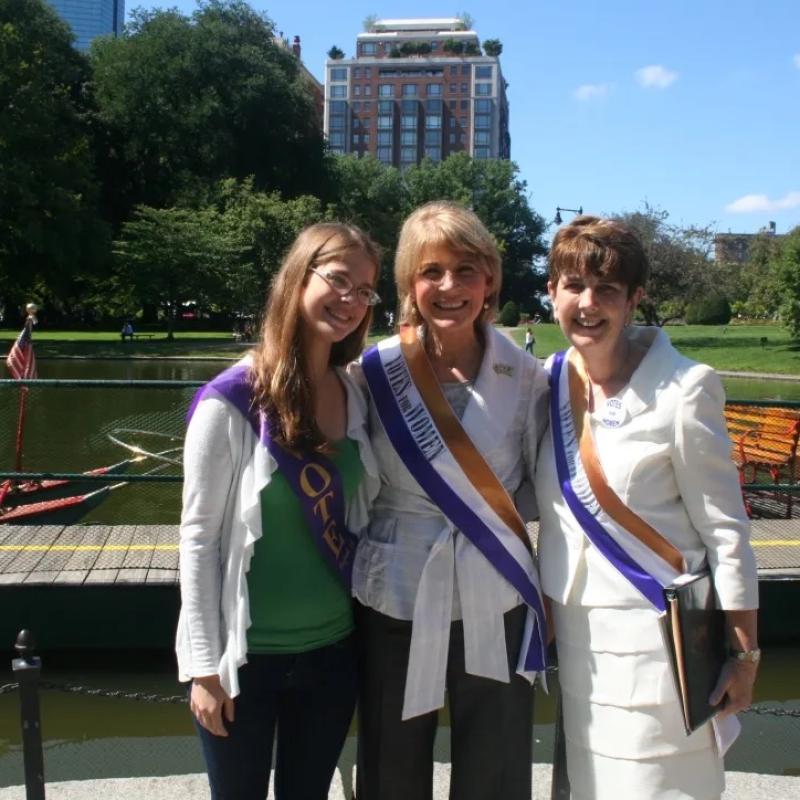 Three women stand outside smiling.