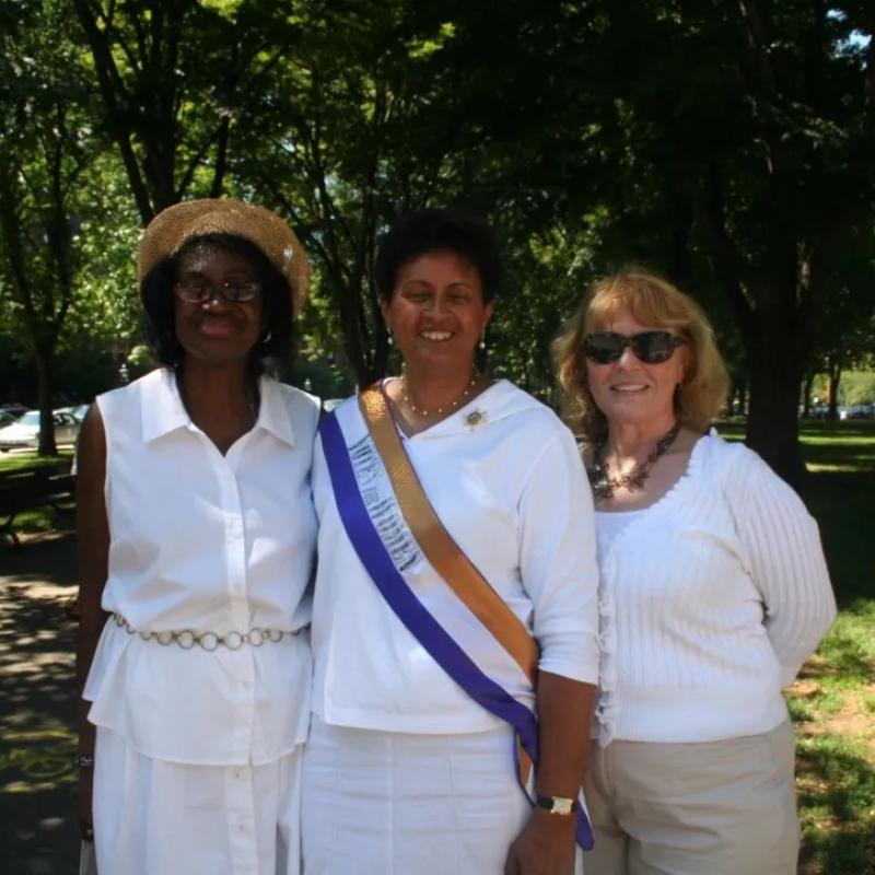 Three women stand outside smiling.