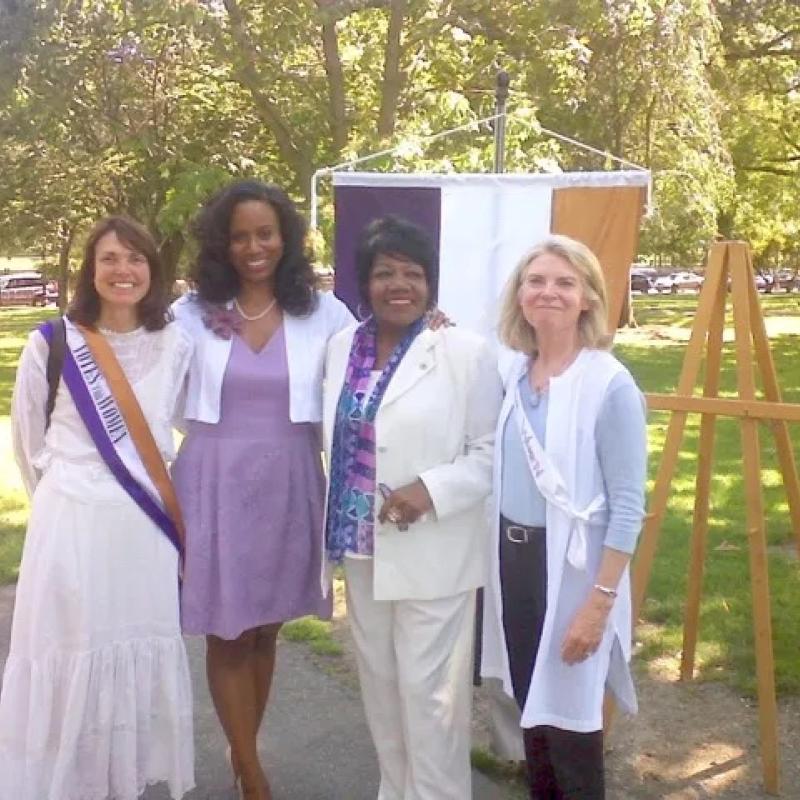 Four women stand outside smiling.