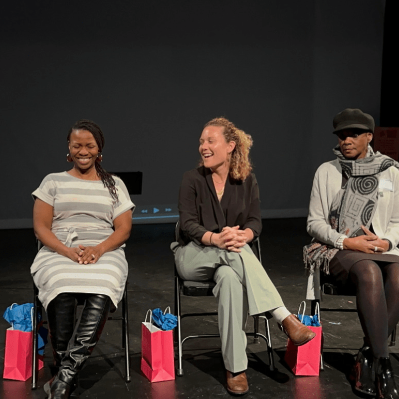 Five women sitting and smiling.