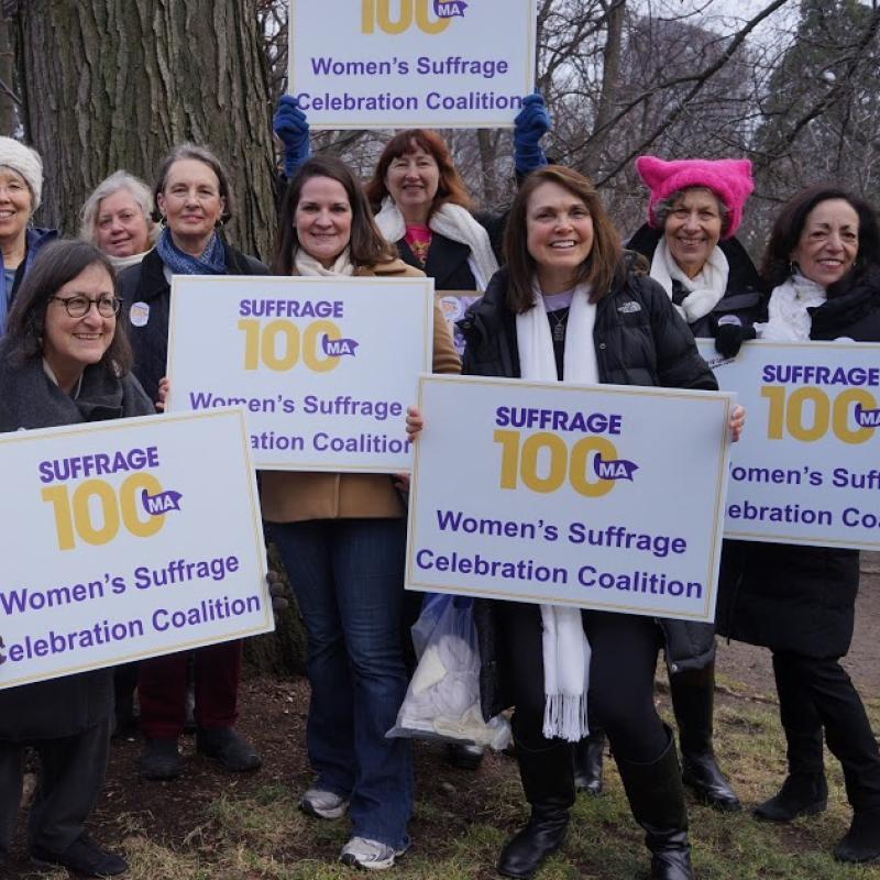 Women hold Suffrage100MA signs.