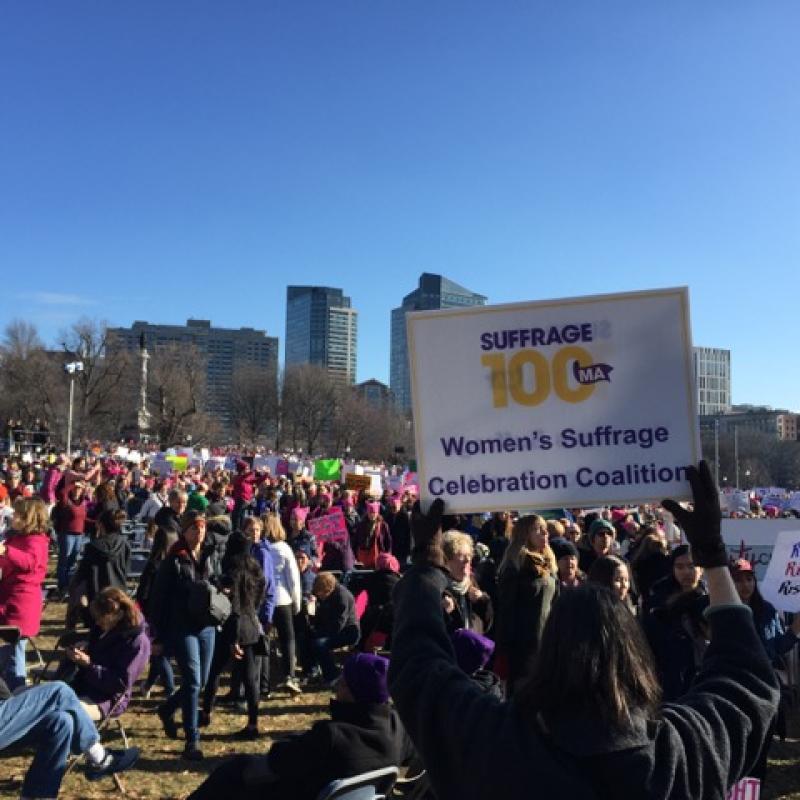 Woman holds Suffrage100MA sign.