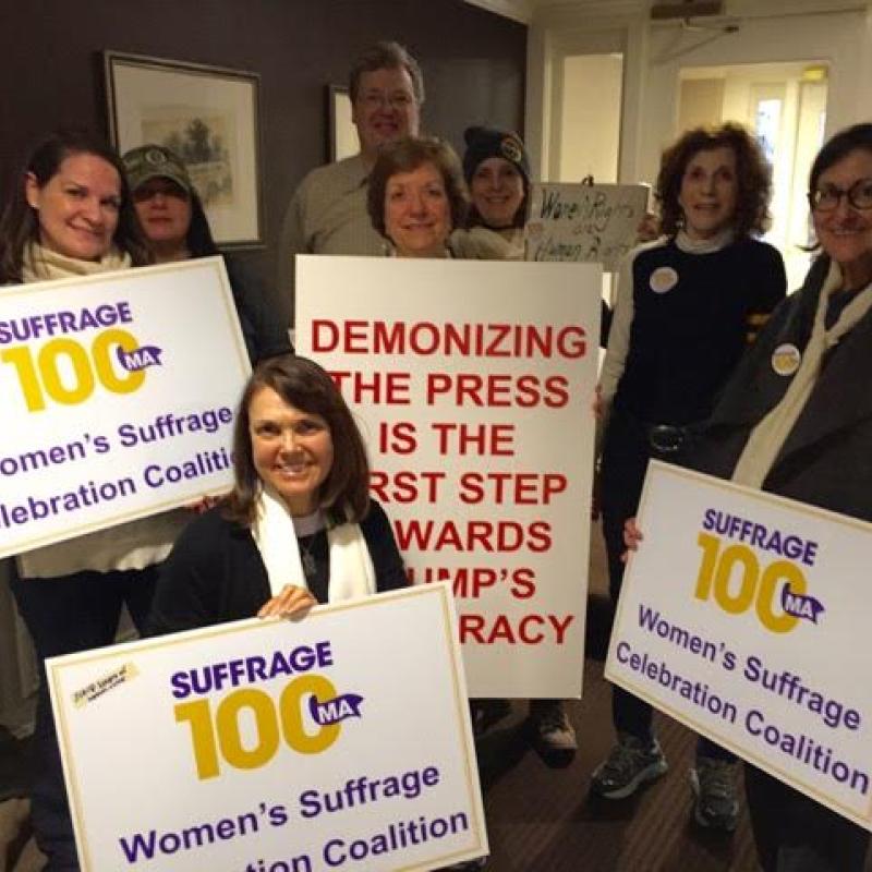 Women hold Suffrage100MA signs.