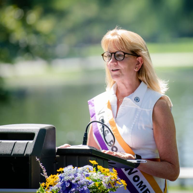 Woman stands at podium speaking.