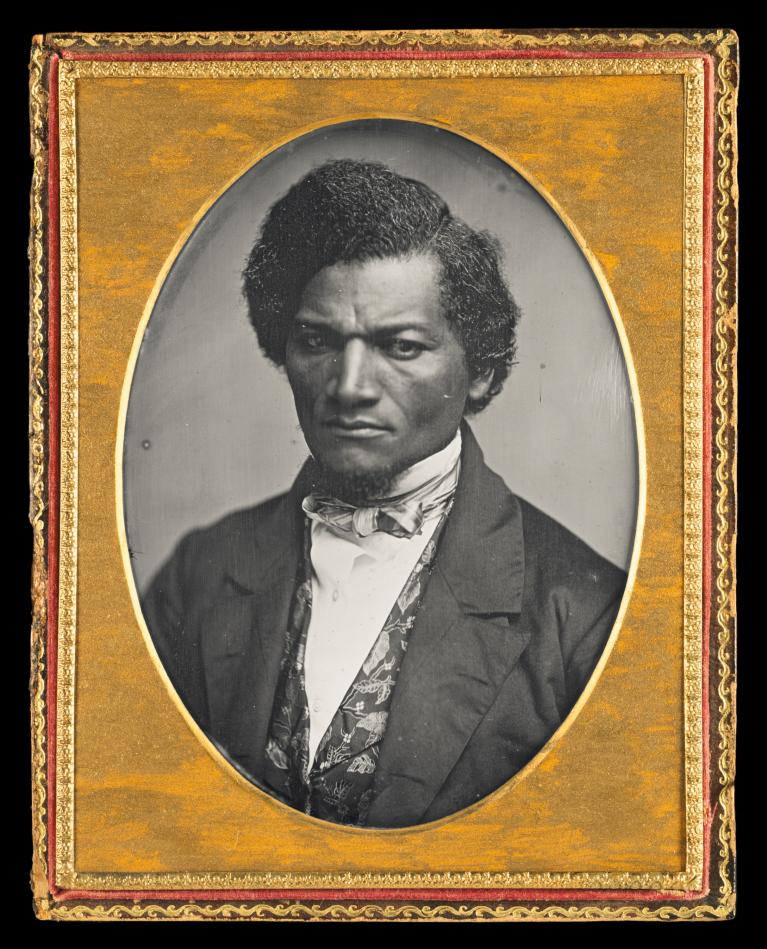 Black and white daguerreotype of Frederick Douglass (aged approximately 29-34) wearing a suit and bearing a stern expression.