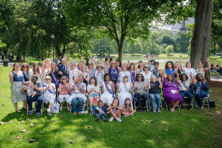 Attendees of 2024 Women's Equality Day event on the Boston Common seated and standing