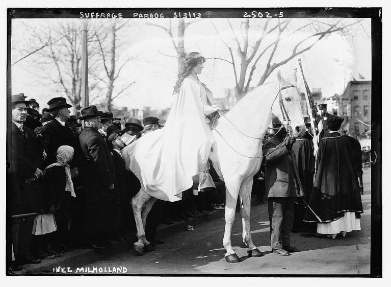 Inez Milholland Boissevain, dressed in white, on horseback in a suffrage parade.