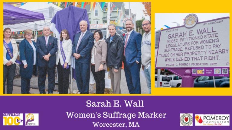 Group of adults stands in front of sign.