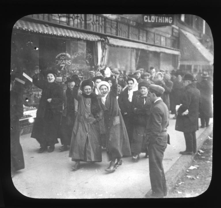 women picketing and waving to the camera