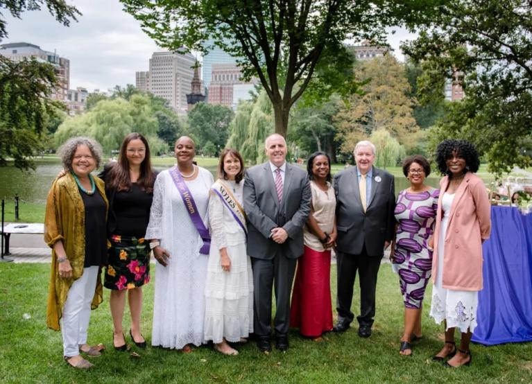 Nine adults stand outside smiling.