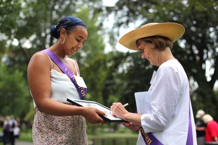 Two women stand outside on lawn.