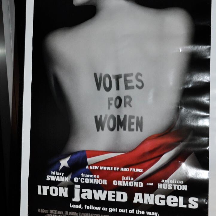 Movie poster of woman's back wrapped with American flag, with written words, "Votes for Women."