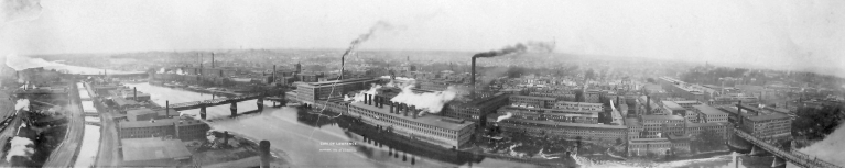 view of the city of Lawrence, filled with industrial brick factory buildings along a river.