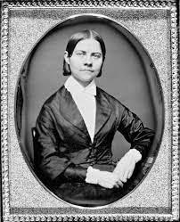 Portrait of a woman sitting wearing a white blouse and a black jacket