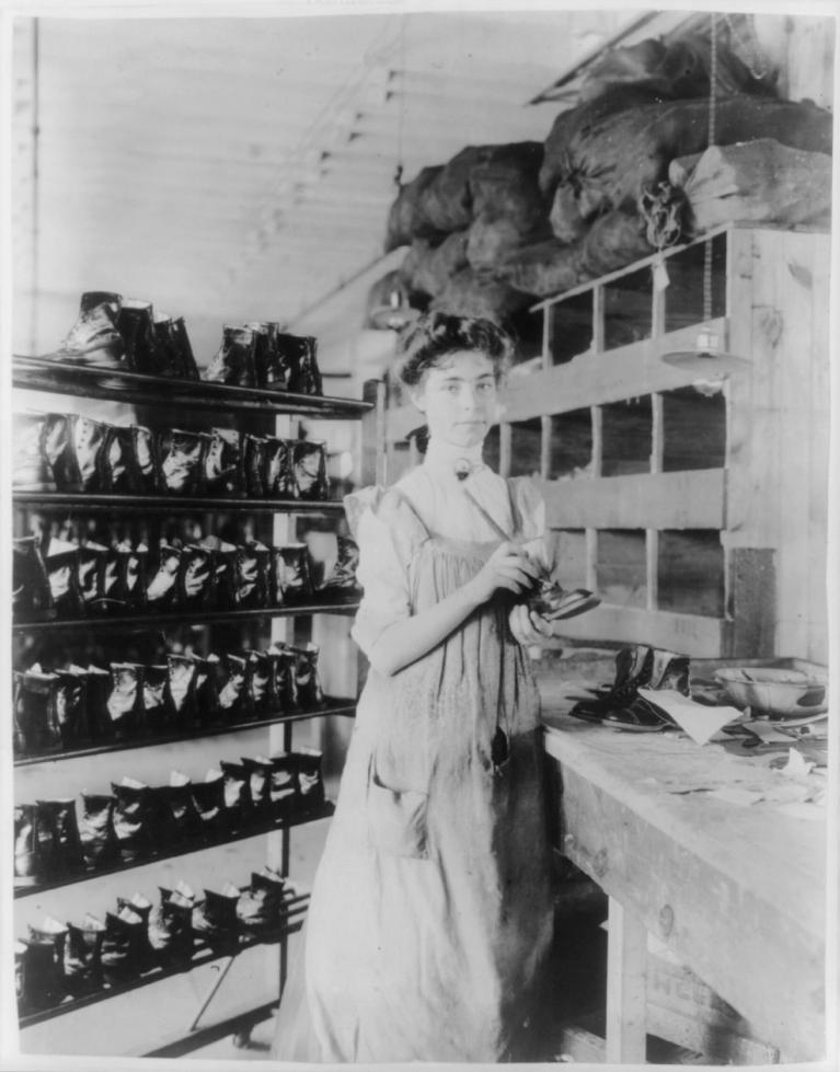 Black and white photo of woman fixing shoes.