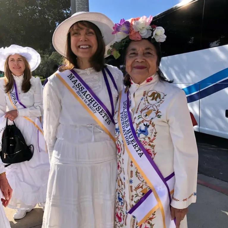 Two women wearing white smiling.