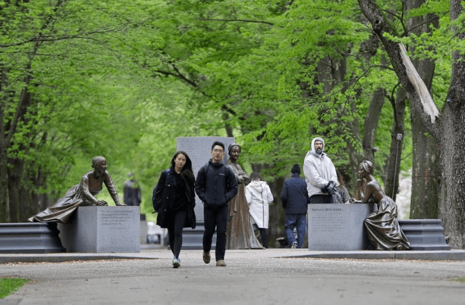 People walking in a park and looking at statues