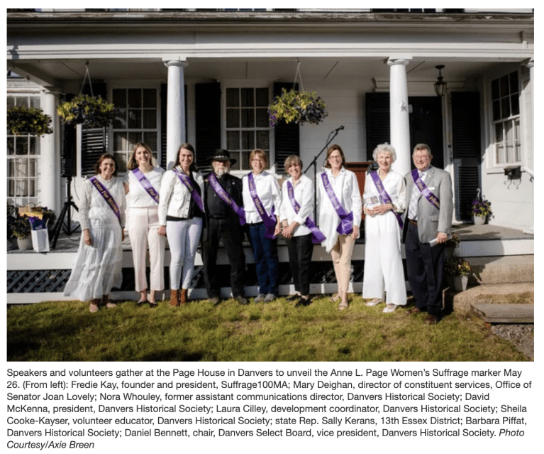 Group of people wearing purple sashes stand outside smiling.