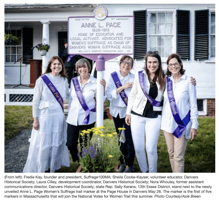 Four women stand outside laughing wearing purple sashes.