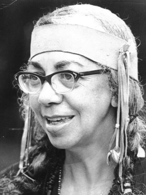 Black and white portrait photo of older woman wearing Native headress.